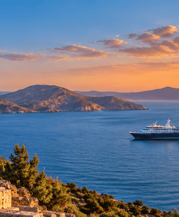 Ancient Greek temple overlooking the Aegean Sea, with islands and a cruise ship at sunset.